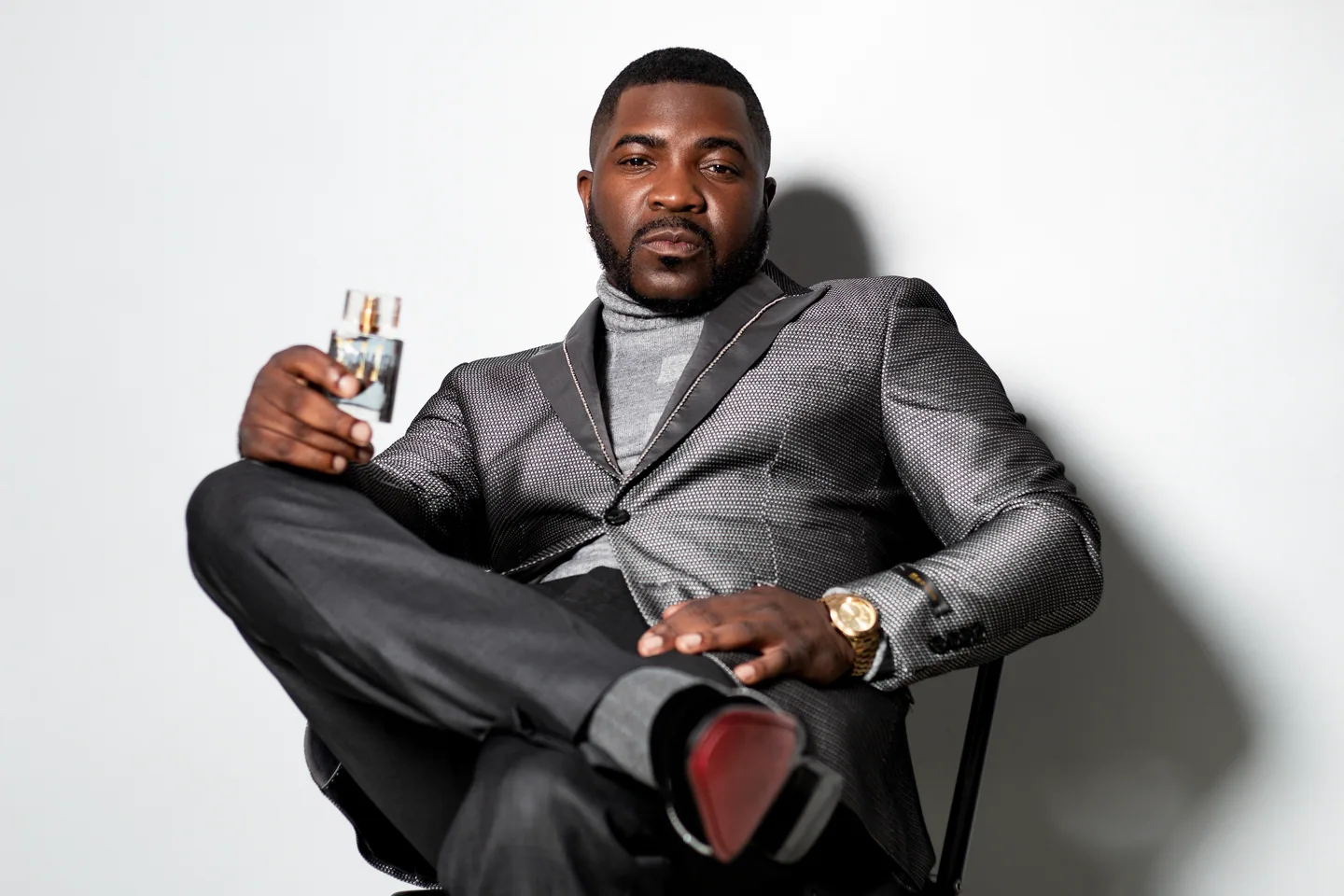 Entrepreneur in a tailored gray suit holding his product against a bright backdrop