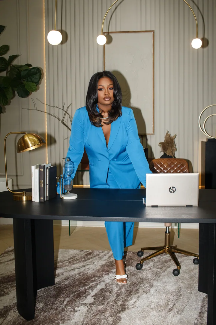 Professional in a vivid blue suit seated at a desk in a bright workspace