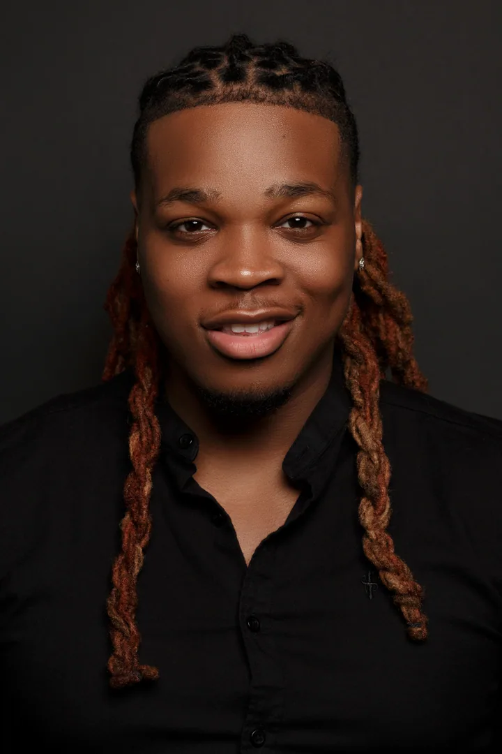 Creative professional with long locs photographed against a dark backdrop