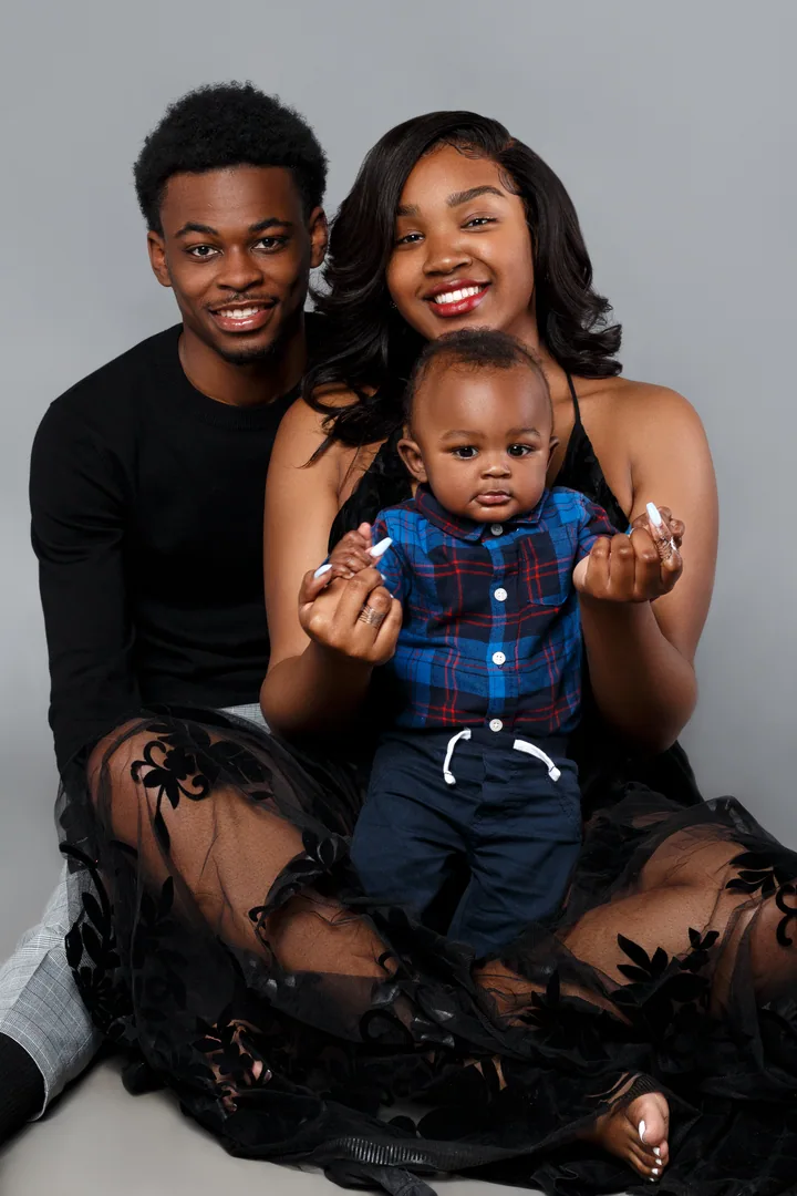 Parents and child smiling together in a dark studio portrait