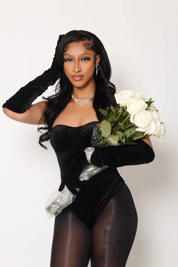 Studio portrait holding white flowers against a pale background